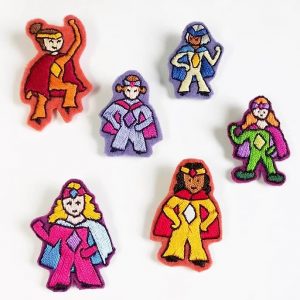 Présentation de 6 broches brodées à la main sur le thème des superwoman. Chaque broche à une forme et couleur différentes